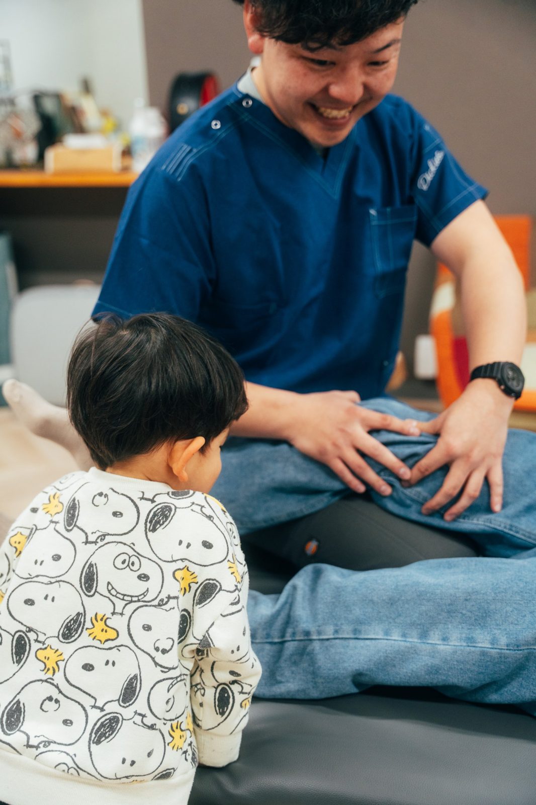 お子さまが見守る中、笑顔で施術する院長